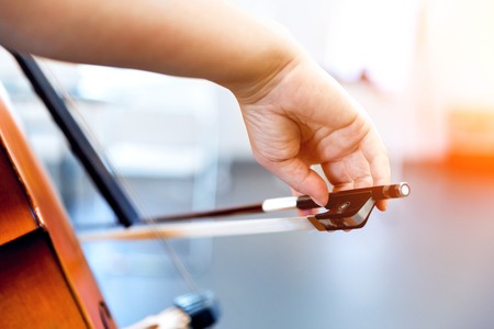 Close up of cello with bow in handsの写真素材