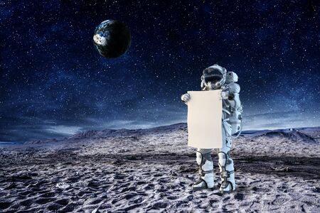 Astronaut in space holding white blank board. Elements of this image are furnished by NASAの写真素材