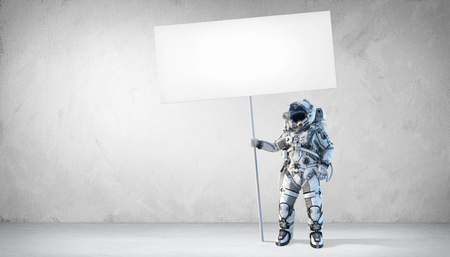 Astronaut holding blank banner for advertise. Mixed mediaの写真素材