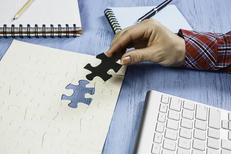 Hand of woman completing puzzle with missing piece