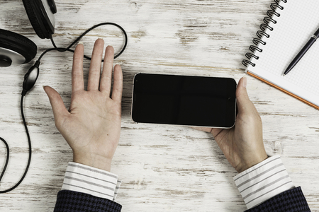 Top view of businesswoman hand with smartphone over white wooden tableの写真素材