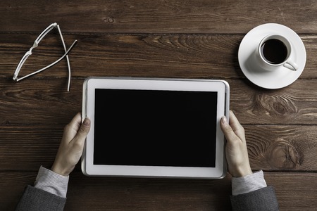 Top view of businesswoman sitting at wooden table and holding tabletの写真素材