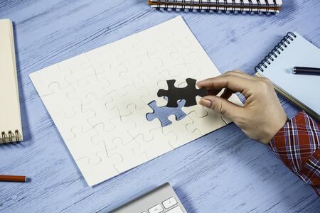 Hand of woman completing puzzle with missing piece
