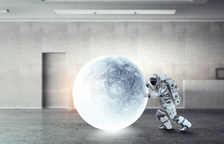 Astronaut in suit making planet roll. Mixed mediaの写真素材