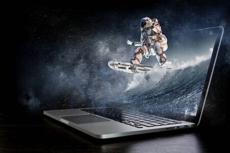 Astronaut coming out of laptop screen. Mixed mediaの写真素材