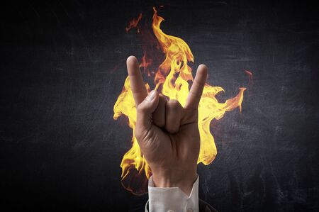 Hand of businessman on concrete background showing rock gesture