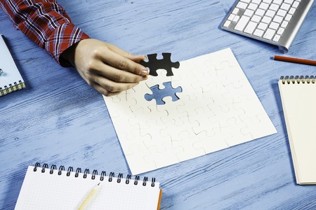 Hand of woman completing puzzle with missing piece