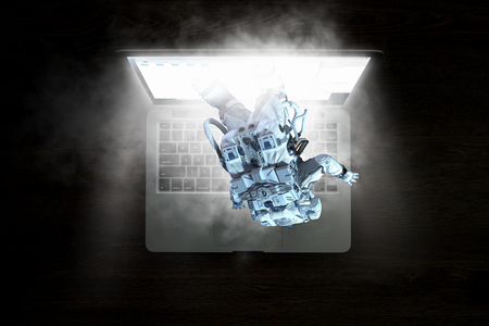 Astronaut coming out of laptop screen. Mixed mediaの写真素材