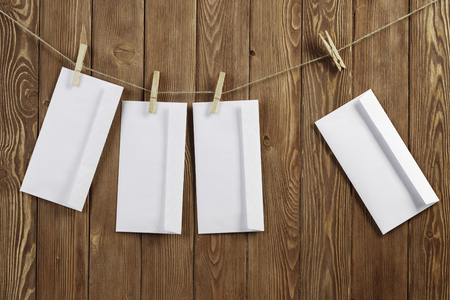 Envelopes hanging on rope on wooden backgroundの写真素材