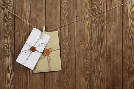 Envelopes hanging on rope on wooden backgroundの写真素材