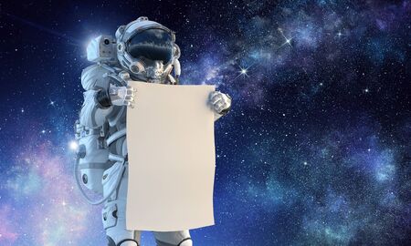 Astronaut in space holding white blank board. Mixed mediaの写真素材