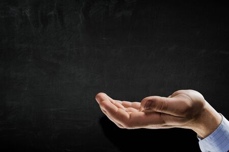Open palm hand gesture of male hand on dark backgroundの写真素材
