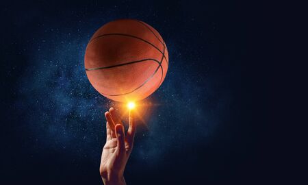 Female hand on dark background touching with finger sport ball . Mixed mediaの写真素材