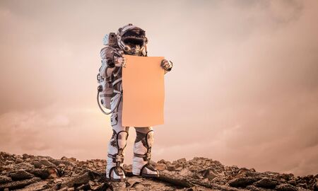 Martian on planet surface with carton banner in hands. Mixed mediaの写真素材