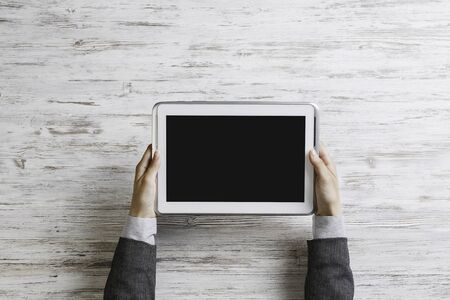 Top view of businesswoman sitting at wooden table and holding tabletの写真素材