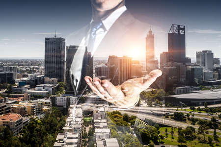 Businessman with opened palm against modern city background . Mixed mediaの写真素材