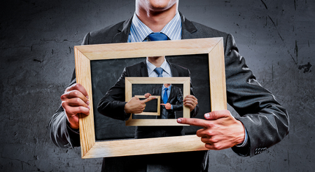 Handsome businessman holding wooden frame with business sketches. Mixed mediaの写真素材