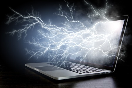 Open laptop with lightning coming from screen on dark background. Mixed mediaの写真素材
