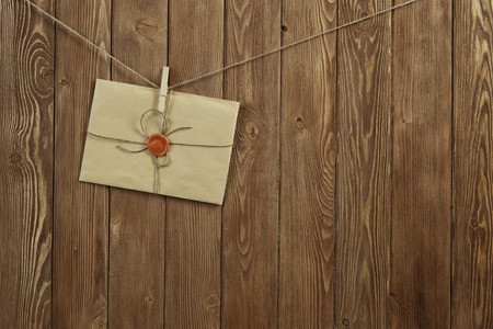 Envelope hanging on rope on wooden backgroundの写真素材