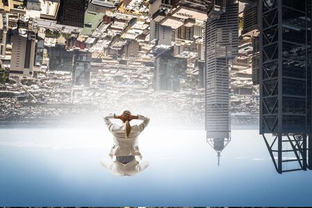 Businesswoman sitting in lotus pose on cloud high in sky