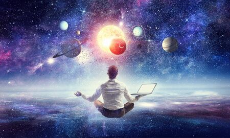 Businessman sitting in lotus position against space background.
