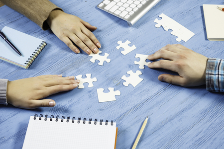 Group of people sitting at table and assembling jigsaw puzzleの写真素材
