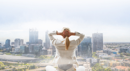 Businesswoman sitting in lotus pose on cloud high in skyの写真素材