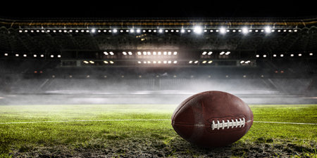 American rugby ball on grass in stadium. Mixed media