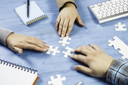 Group of people sitting at table and assembling jigsaw puzzleの写真素材