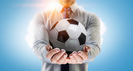 Close of male hand holding soccer ball in palmsの写真素材