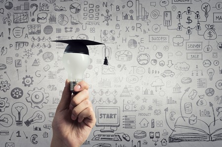 Hand of businessman holding glowing light bulb with graduation hat on itの写真素材