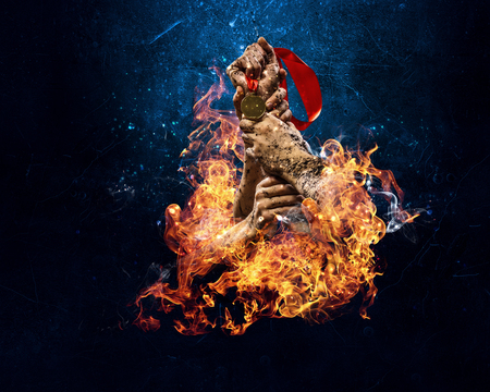 Man arm holding burning medal on dark backgroundの写真素材