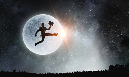 Silhouette of businessman over moon . Mixed mediaの写真素材