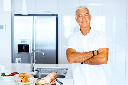Portrait of a smart senior man with standing in kitchenの写真素材