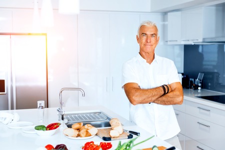 Portrait of a smart senior man with standing in kitchenの写真素材