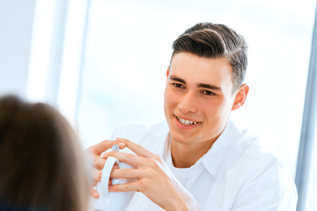 Happy young woman with cup of tea or coffee at homeの写真素材