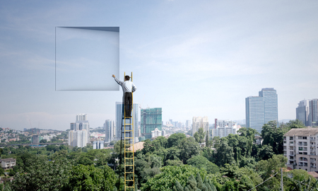 Businessman standing on ladder and climbing up to window. Mixed mediaの写真素材