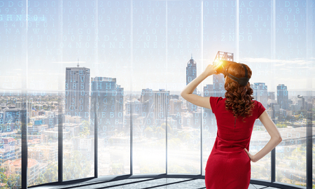 Woman in red dress wearing virtual reality helmet. Mixed mediaの写真素材