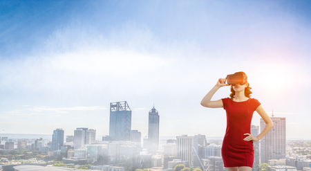 Woman in red dress wearing virtual reality helmet. Mixed mediaの写真素材