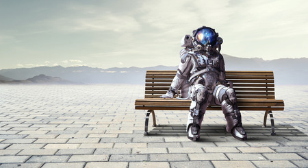 Spaceman sitting on wooden bench. Mixed mediaの写真素材