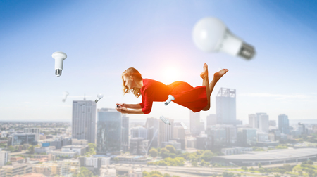 Woman fly in air and use mobile. Mixed mediaの写真素材