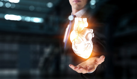 Man s hands showing anatomical heart model. Mixed media.の写真素材