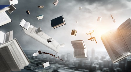 Young man in hat and casual clothes levitating over city with books and objects around. Mixed mediaの写真素材