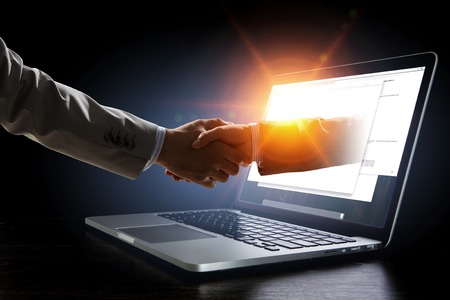 Business handshake by a man and a woman, and a laptop.の写真素材