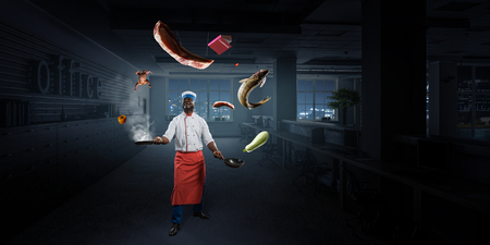 Black man wearing an apron and cooking in action. Mixed mediaの写真素材