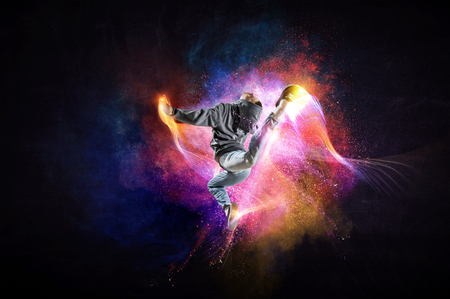 Modern female dancer jumping in hoodie with colourful splashes background. Mixed mediaの写真素材