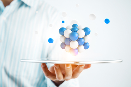Businessman hand holding a tabalet with a bunch of spheres levitating above. Mixed mediaの写真素材