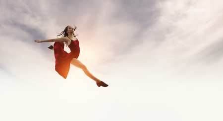 Young and beautiful female dancer in a red dress. Mixed mediaの写真素材