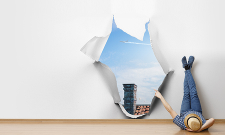 Young man lying on the floor with legs raised up on the wall. Mixed mediaの写真素材