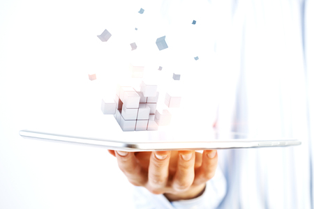Businessman hand holding a tabalet with abstract cube puzzle. Mixed mediaの写真素材